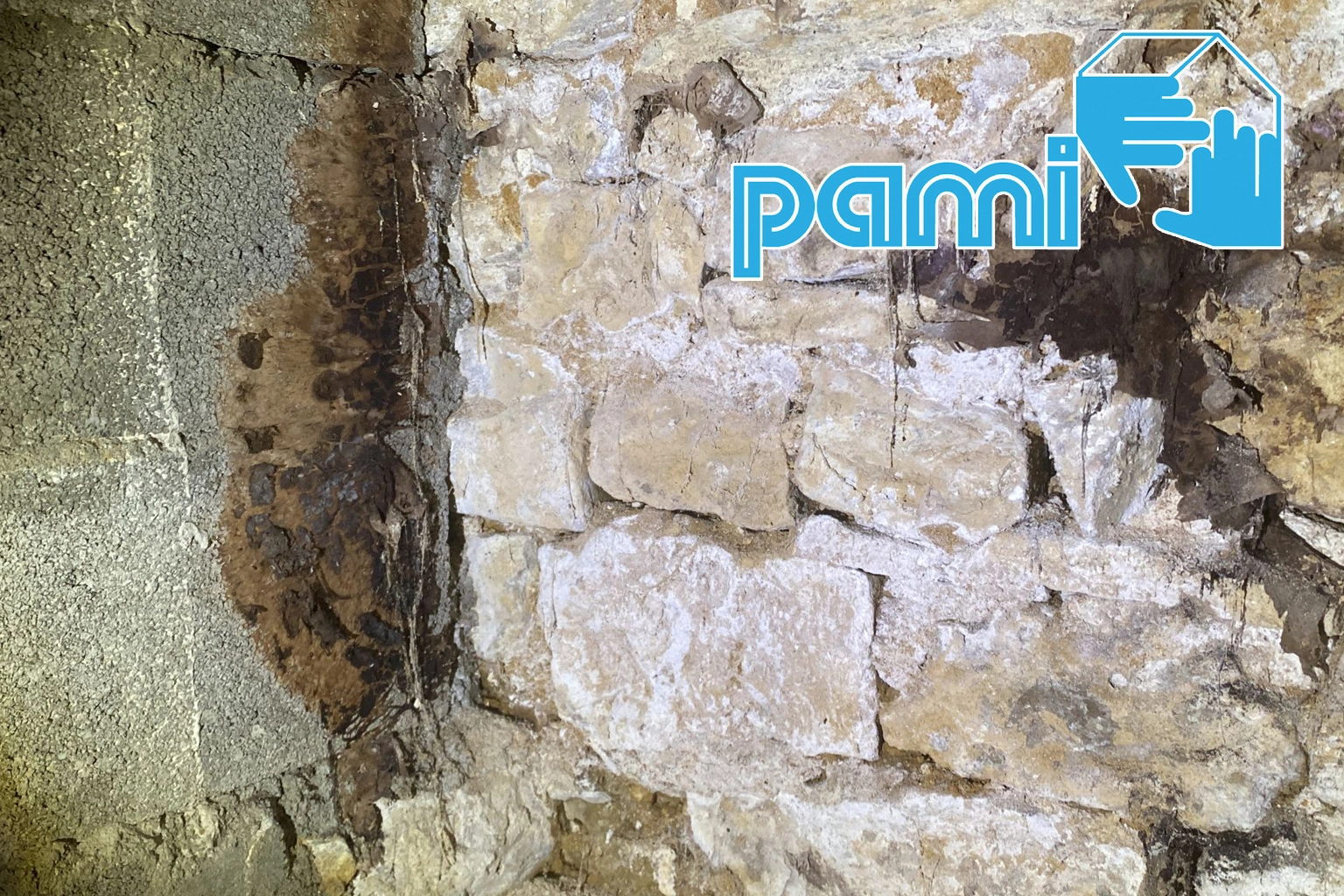 Mur en pierre avec des traces blanchâtres et brun foncé et des zones de maçonnerie dégradées dans le Lot